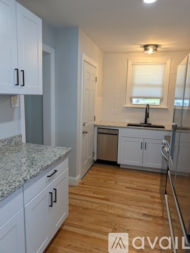 A kitchen with white cabinets and a granite countertop.