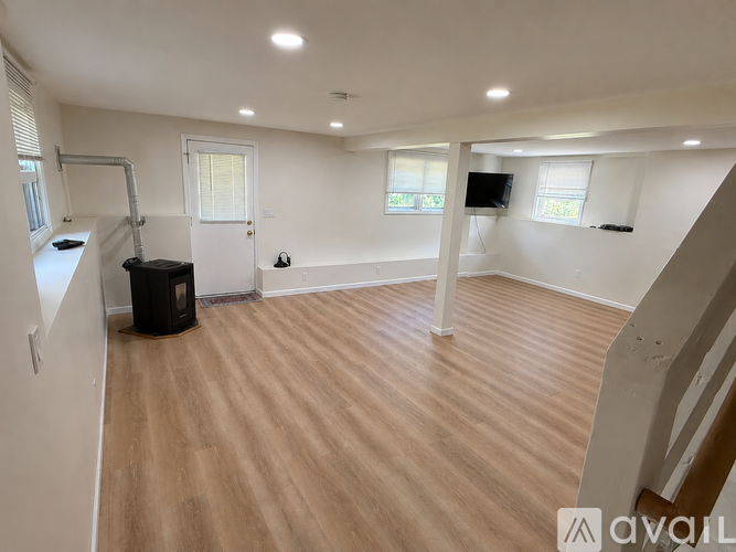 A spacious room with wooden flooring and white walls.