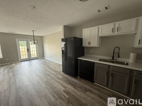 A kitchen with a black refrigerator and white cabinets.