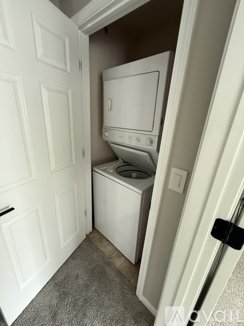 A white door opens to a small laundry room with a washer and dryer.