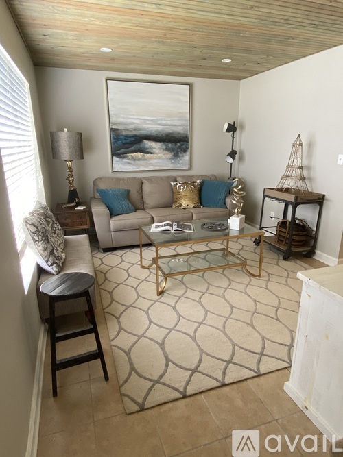 A living room with a couch, a chair, a table, and a painting on the wall.