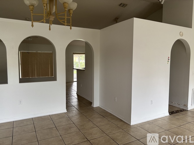 A spacious room with arched doorways and a chandelier.