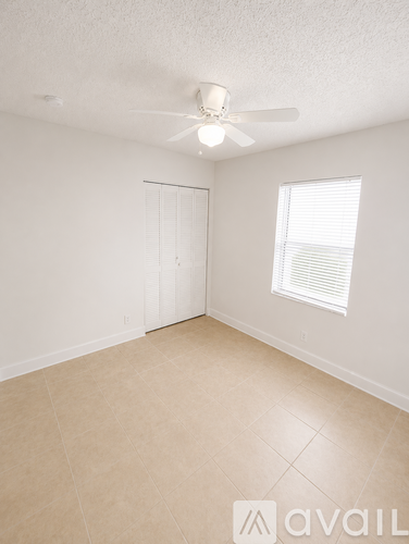 A room with a ceiling fan and a window with blinds.
