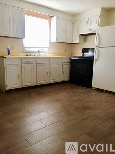 A kitchen with wooden floors and white appliances.