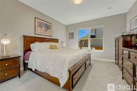 A bedroom with a large bed, a dresser, and a nightstand with a lamp.