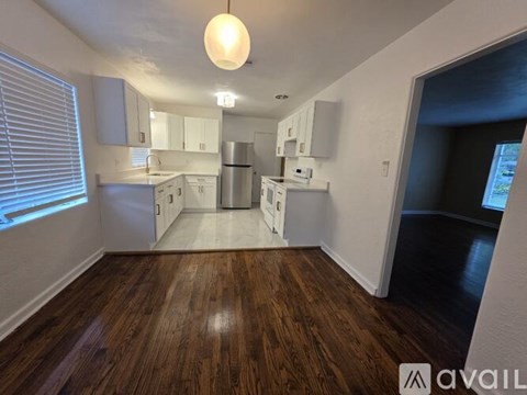 A kitchen with white cabinets and a wooden floor.