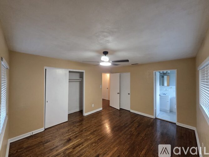 A spacious room with wooden floors and a ceiling fan.