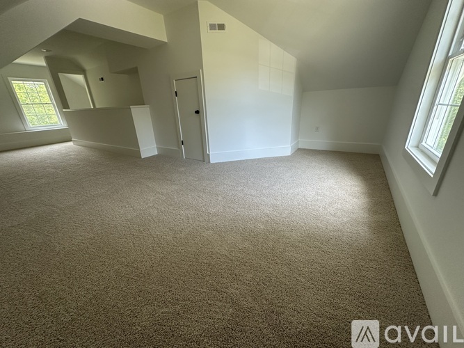 A spacious room with carpeted floor and a window on the left side.