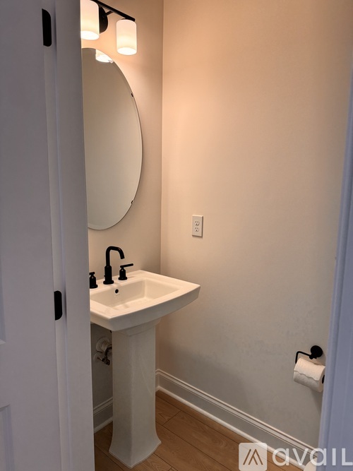 A white sink with a round mirror above it.