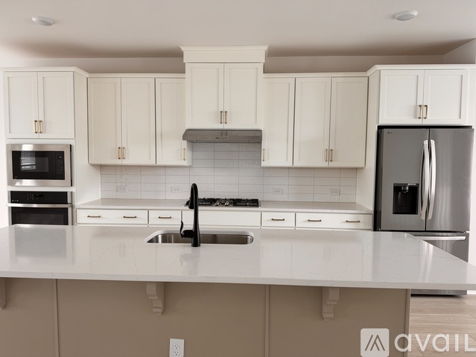 A kitchen with white cabinets and a stainless steel refrigerator.
