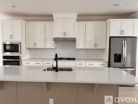 A kitchen with white cabinets and a stainless steel refrigerator.