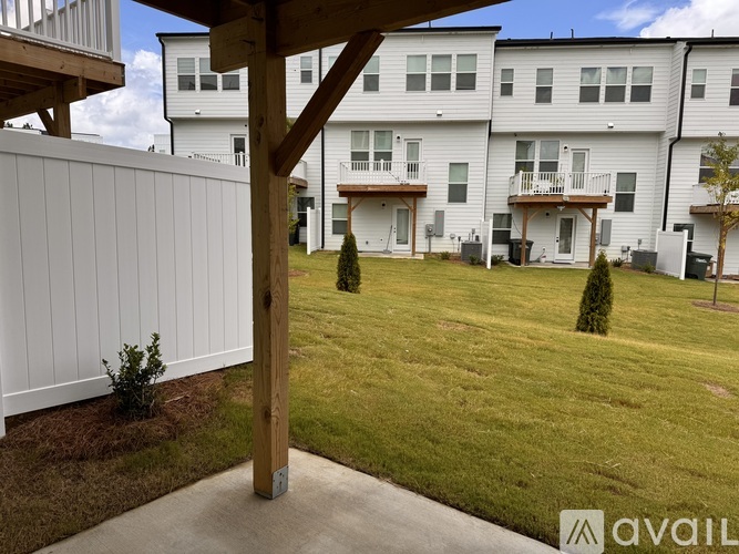 A white fence with a small tree in front of a building.