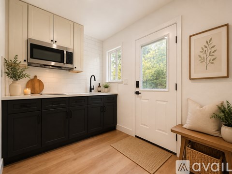 A kitchen with black cabinets and a white door.