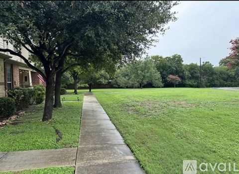 A tree-lined sidewalk in front of a house.