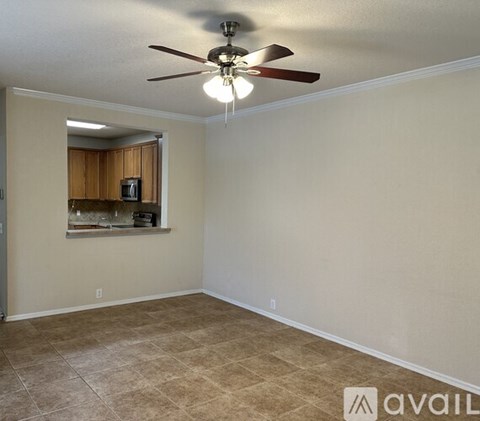 A room with a ceiling fan and a window overlooking a kitchen.