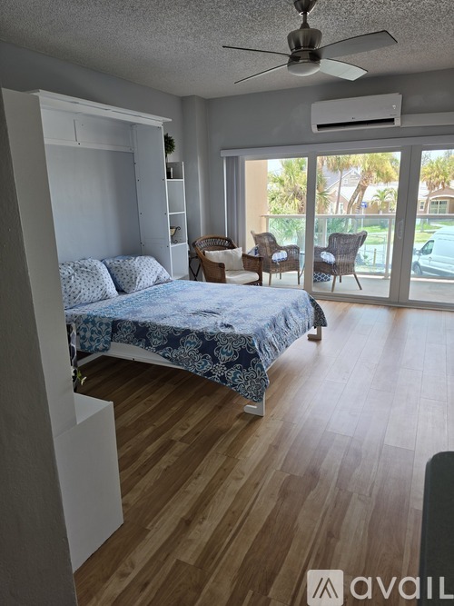 A bedroom with a bed, chair, and sliding glass doors.