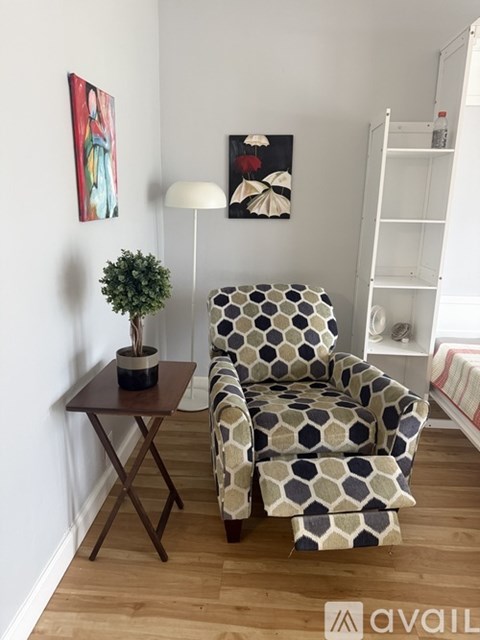 A chair with a geometric pattern sits in a room with a small table and a potted plant.