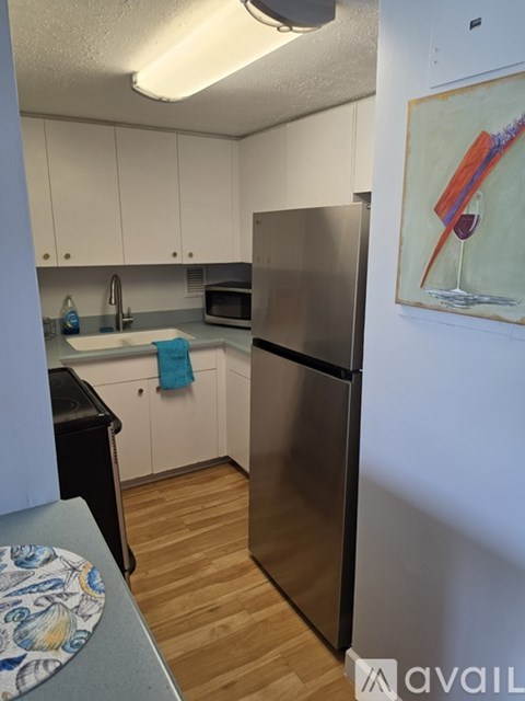 A kitchen with a refrigerator, microwave, and sink.