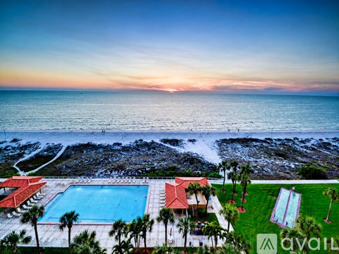A beachfront property with a pool and palm trees.