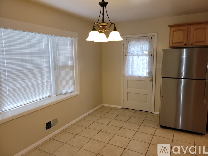 A kitchen with a stainless steel refrigerator and a chandelier hanging from the ceiling.