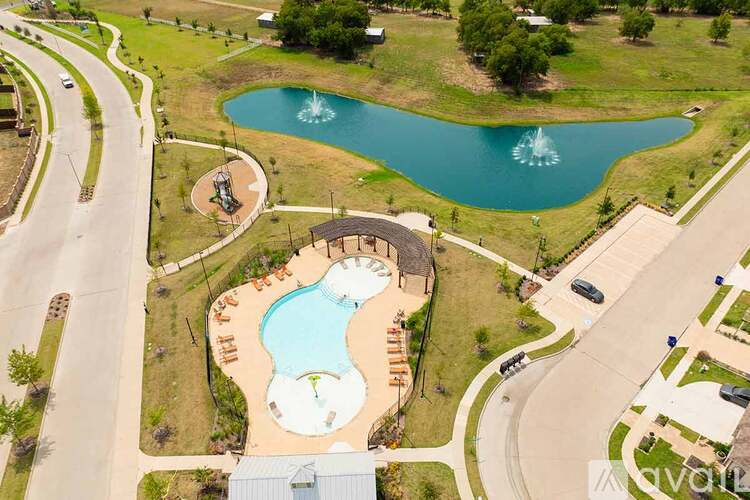 A large outdoor swimming pool with a fountain in the middle of a grassy area.
