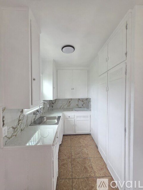 A kitchen with white cabinets and marble countertops.