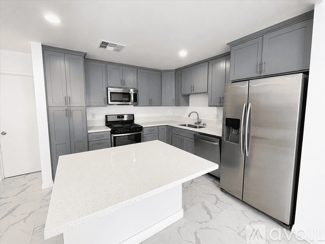 A modern kitchen with a marble countertop and stainless steel appliances.