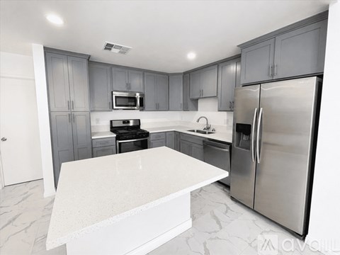 A modern kitchen with a marble countertop and stainless steel appliances.