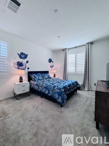 A bedroom with a bed, nightstands, and a chandelier.