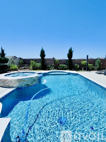 A pool with a waterfall and a water feature in the middle.