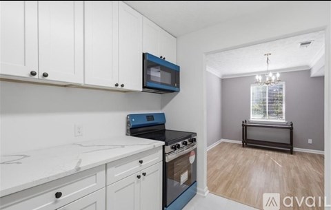 A kitchen with white cabinets and a black microwave.