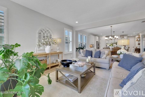 A living room with a glass coffee table and a large plant.