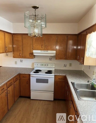 A kitchen with wooden cabinets and a white stove top oven.