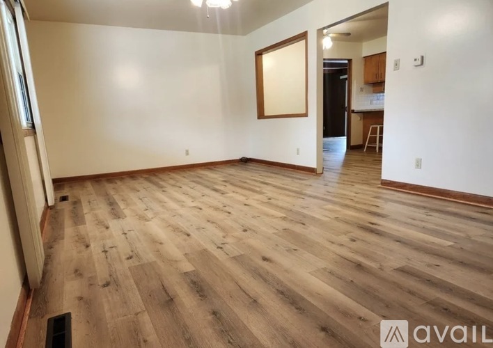 A spacious room with wooden flooring and a doorway leading to another room.