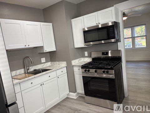 A kitchen with white cabinets and a black microwave above the stove.