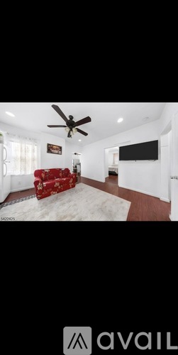 A living room with a red couch and a ceiling fan.