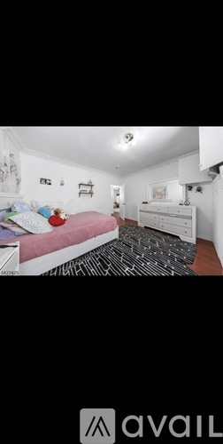 A bedroom with a bed, dresser, and a patterned rug.
