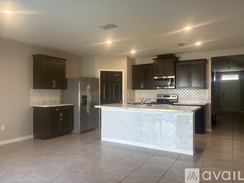 A kitchen with a white countertop and dark brown cabinets.