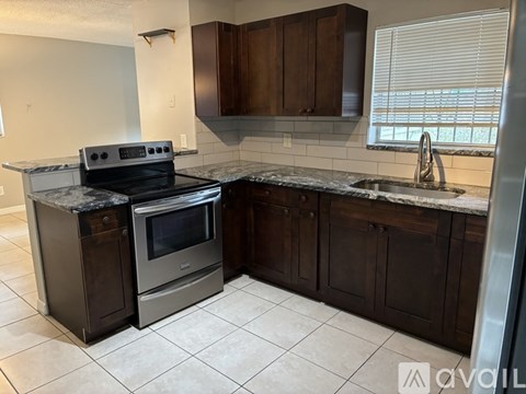 A kitchen with dark wood cabinets and a granite countertop.