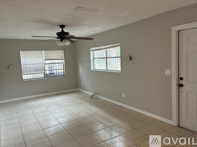 A room with a ceiling fan and two windows.