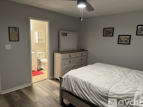 A bedroom with a bed, dresser, mirror, and pictures on the wall.