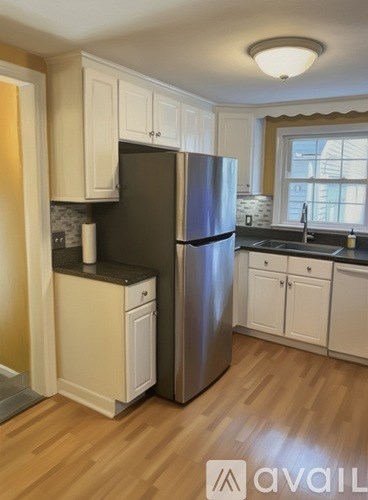 A kitchen with a stainless steel refrigerator and wooden floors.
