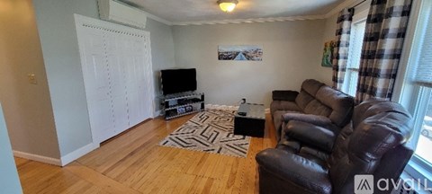 A living room with a brown leather couch and a television.