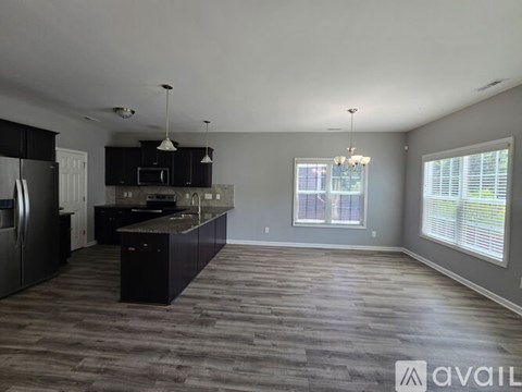 A spacious kitchen with dark wood flooring and modern appliances.