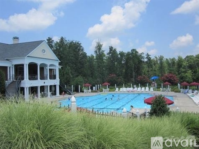 A pool area with a house and trees in the background.