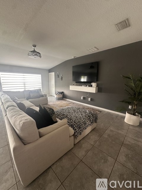 A living room with a large couch and a flat screen TV mounted on the wall.
