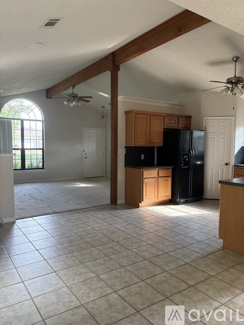 A kitchen with tile flooring and a black refrigerator.