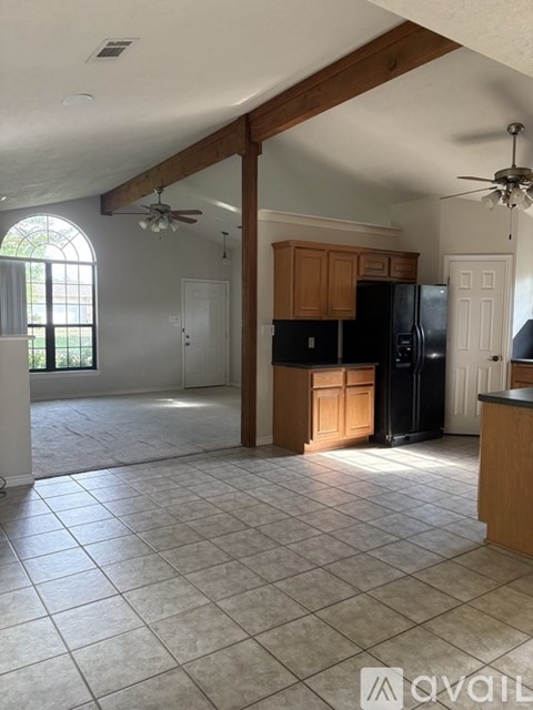 A kitchen with tile flooring and a black refrigerator.