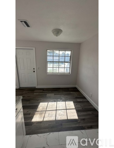 A room with a window and wooden flooring.
