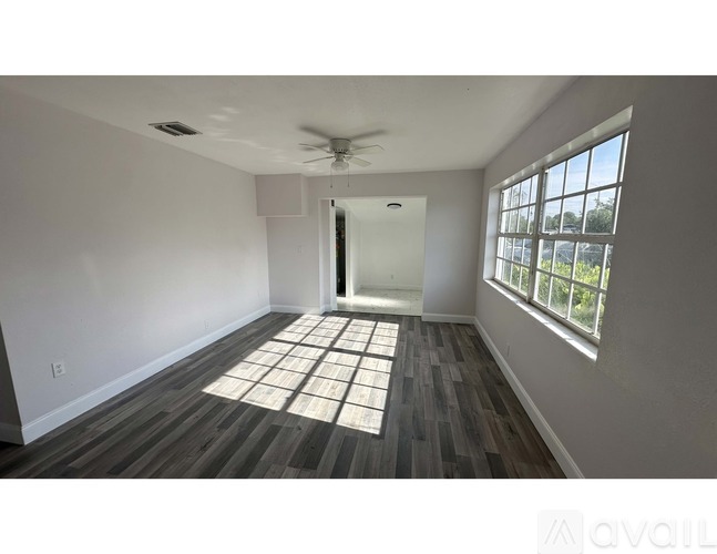 A spacious room with wooden flooring and a ceiling fan.